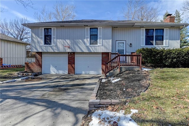 raised ranch with brick siding, driveway, a chimney, and an attached garage