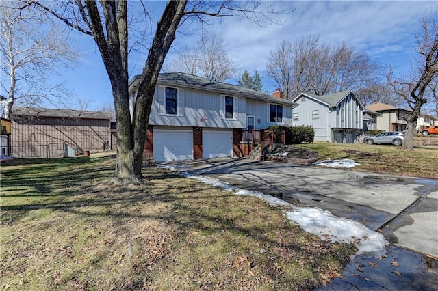 view of front facade with brick siding, a chimney, a garage, driveway, and a front lawn