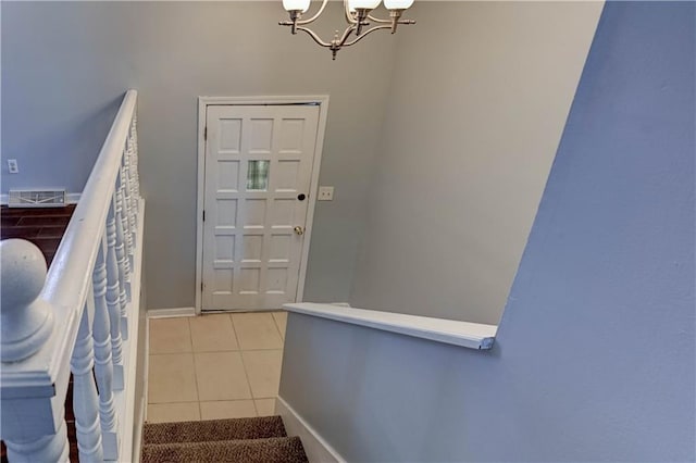 foyer featuring baseboards, light tile patterned flooring, and a notable chandelier