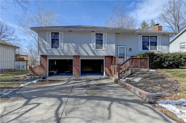 raised ranch with a garage, brick siding, driveway, and a chimney