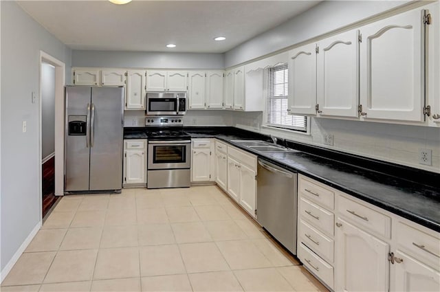 kitchen with dark countertops, white cabinetry, appliances with stainless steel finishes, and a sink