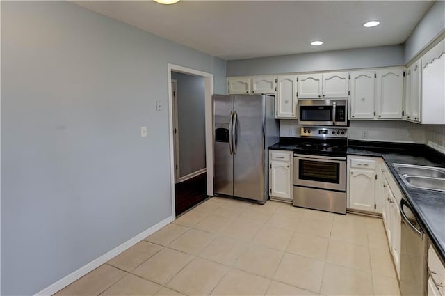 kitchen with dark countertops, white cabinetry, stainless steel appliances, and a sink