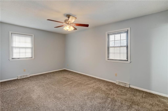 carpeted spare room featuring baseboards and visible vents