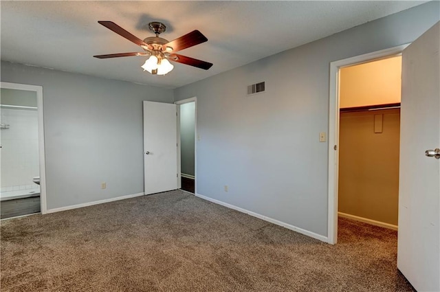 unfurnished bedroom featuring carpet, visible vents, a spacious closet, and baseboards