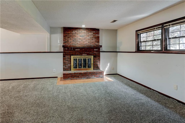 unfurnished living room with baseboards, visible vents, a textured ceiling, carpet flooring, and a brick fireplace