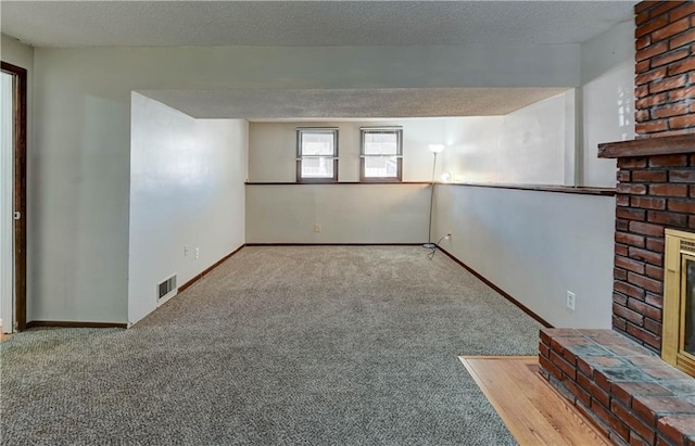 interior space with visible vents, a fireplace, a textured ceiling, and baseboards