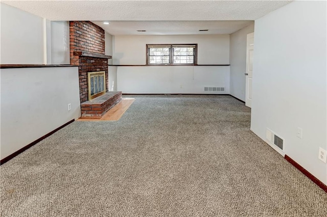 unfurnished living room with a textured ceiling, a fireplace, visible vents, and carpet flooring