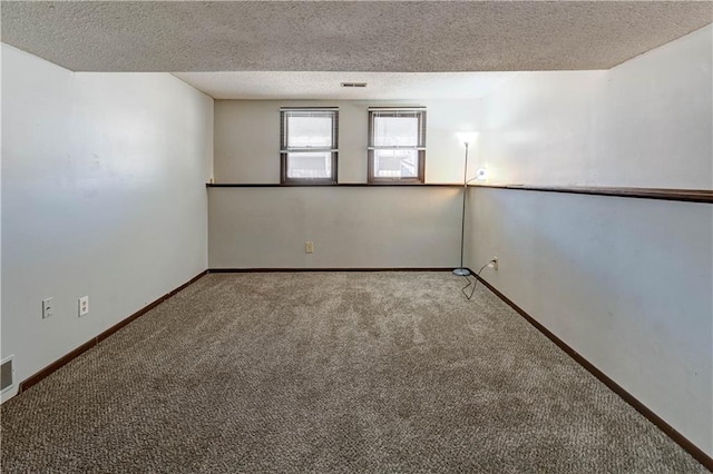 carpeted spare room featuring visible vents, a textured ceiling, and baseboards