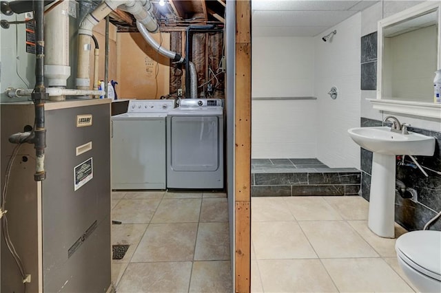 interior space with toilet, tile patterned flooring, a sink, and washer and dryer