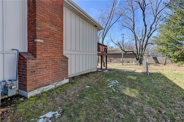 view of side of home featuring board and batten siding, fence, and a lawn