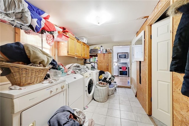 washroom featuring cabinet space, independent washer and dryer, and light tile patterned floors