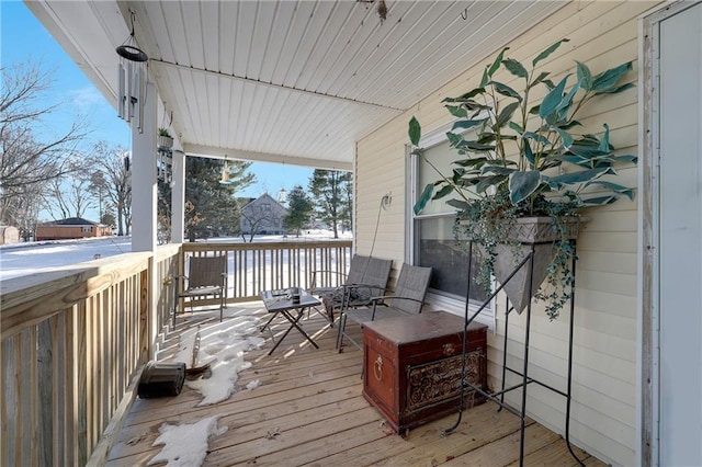 snow covered deck featuring covered porch