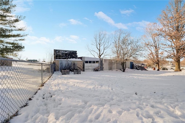 snowy yard with a detached garage and fence