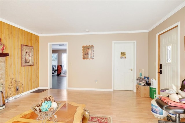 living area with ornamental molding, wooden walls, baseboards, and wood finished floors