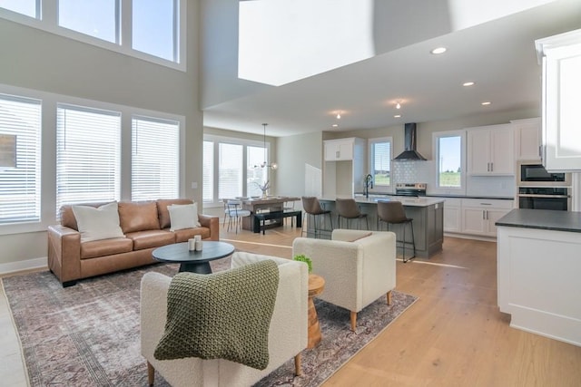 living area featuring baseboards, light wood-style flooring, a wealth of natural light, and recessed lighting