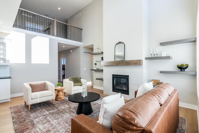 living area featuring light wood finished floors, baseboards, a fireplace, and visible vents