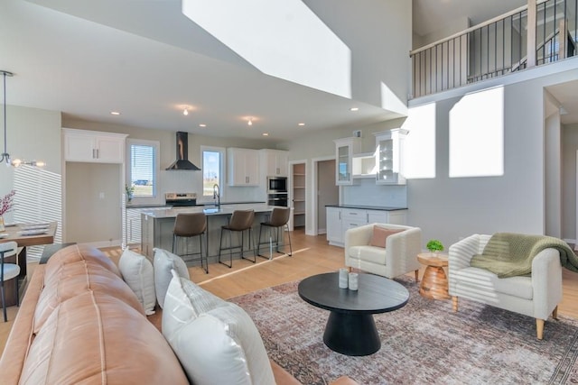 living area with light wood-type flooring, recessed lighting, and a high ceiling