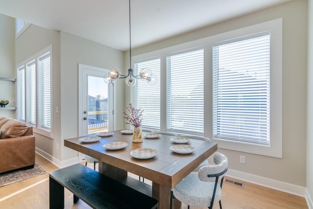 dining room with a notable chandelier, light wood-style flooring, visible vents, and baseboards