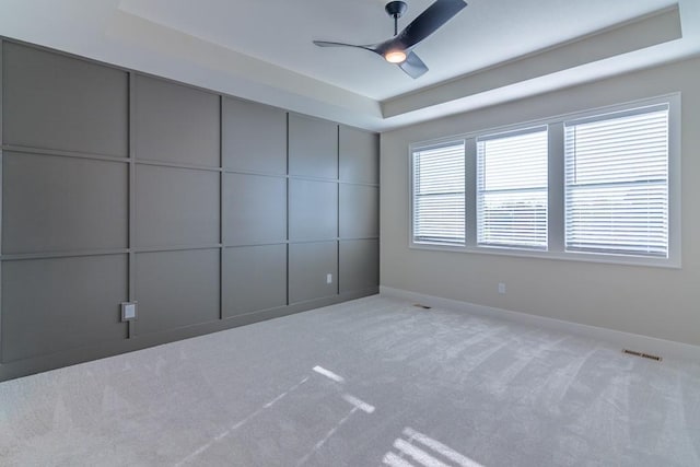 empty room featuring light carpet, ceiling fan, visible vents, and baseboards