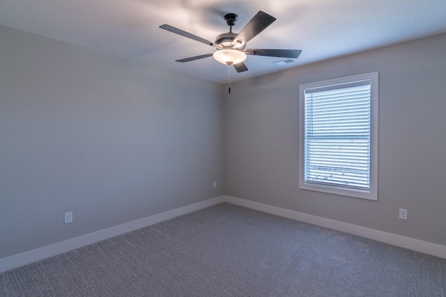 spare room featuring a ceiling fan, dark colored carpet, visible vents, and baseboards