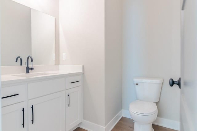 half bathroom featuring toilet, vanity, and baseboards