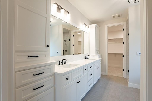 full bath with double vanity, a shower stall, a spacious closet, and a sink