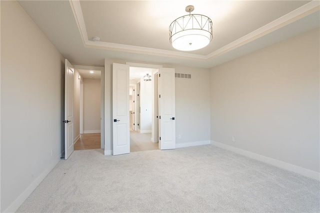 unfurnished bedroom with a tray ceiling, baseboards, visible vents, and carpet flooring