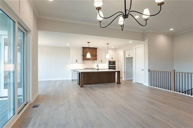 kitchen featuring visible vents, light wood-style flooring, appliances with stainless steel finishes, crown molding, and a notable chandelier