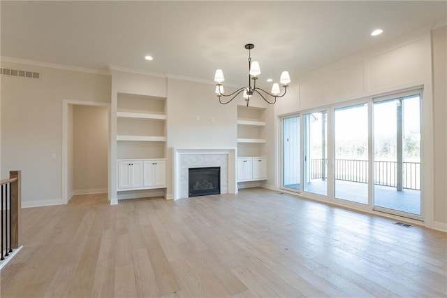 unfurnished living room featuring a notable chandelier, light wood-style flooring, visible vents, and built in features