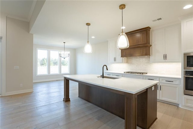 kitchen featuring stainless steel appliances, a sink, light wood-style flooring, and decorative backsplash