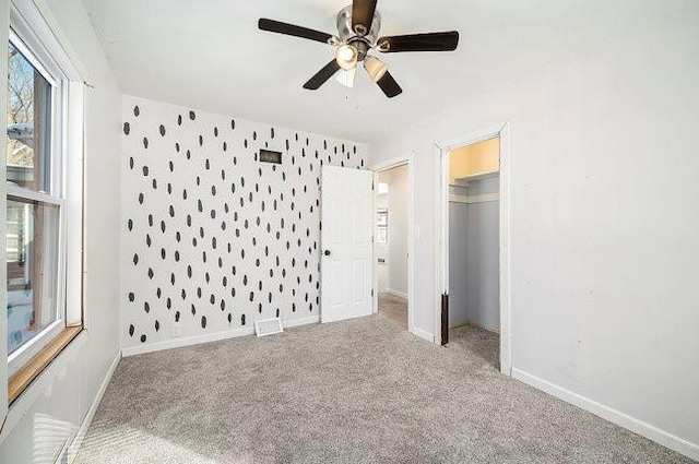 unfurnished bedroom with wallpapered walls, visible vents, baseboards, light colored carpet, and a closet