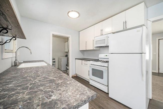 kitchen featuring dark countertops, white appliances, white cabinetry, and a sink