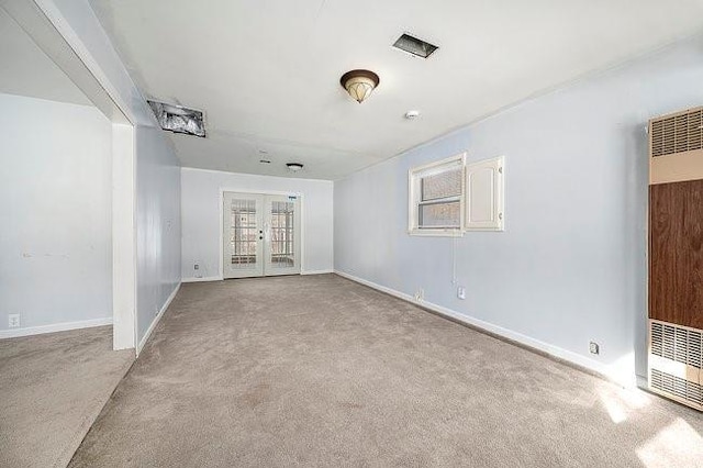 unfurnished room featuring light carpet, a heating unit, a wealth of natural light, and french doors