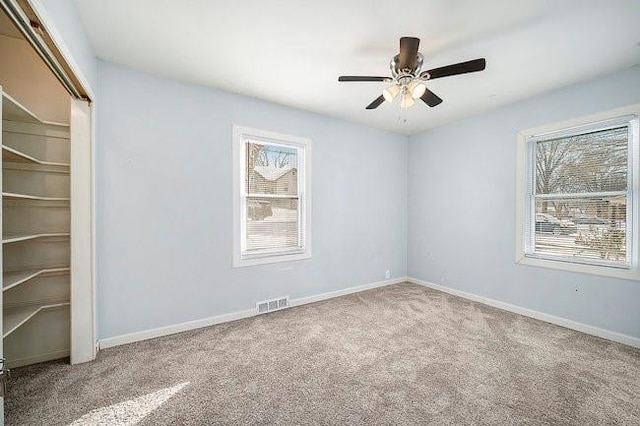 unfurnished room featuring baseboards, ceiling fan, visible vents, and light colored carpet