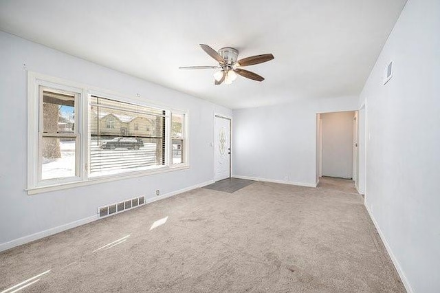 spare room featuring a ceiling fan, visible vents, light carpet, and baseboards