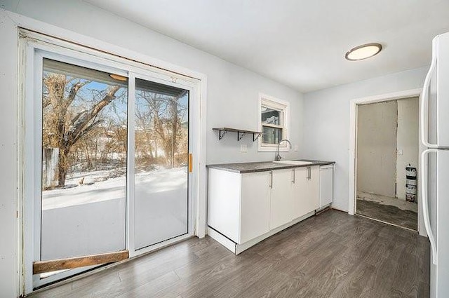 kitchen with a wealth of natural light, dark wood-style floors, white cabinets, and a sink