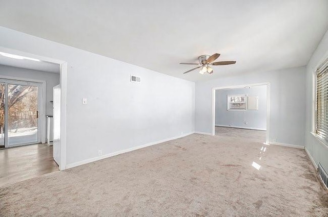 unfurnished room with carpet floors, visible vents, ceiling fan, and baseboards