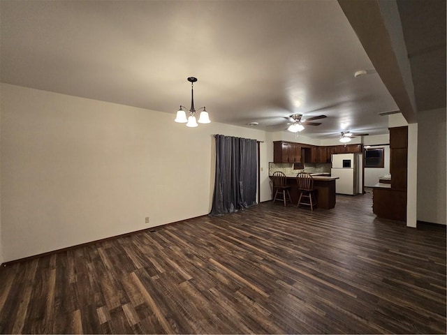 unfurnished living room featuring dark wood finished floors and ceiling fan with notable chandelier