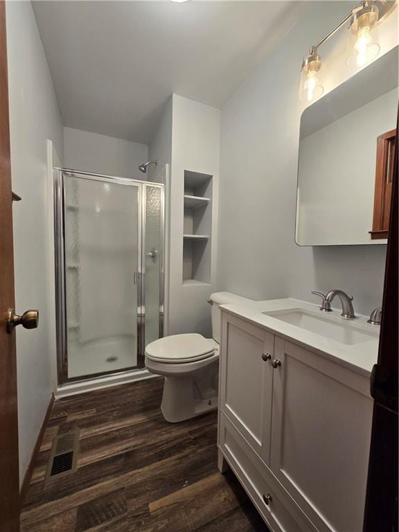 bathroom with toilet, a stall shower, wood finished floors, and vanity