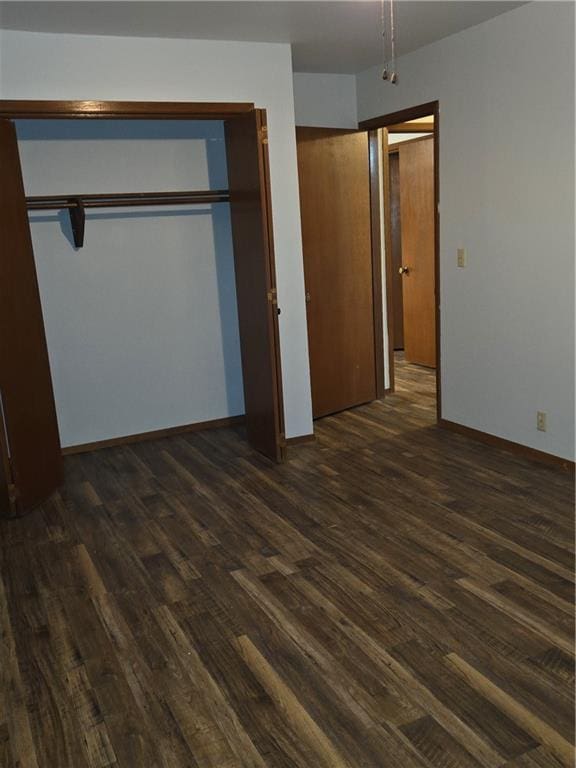 unfurnished bedroom with multiple closets, baseboards, and dark wood-style flooring