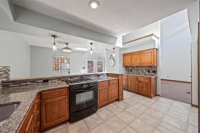 kitchen featuring tasteful backsplash, brown cabinets, dark stone countertops, french doors, and gas stove