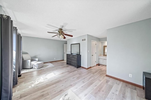 unfurnished living room featuring a textured ceiling, visible vents, a ceiling fan, baseboards, and light wood-type flooring