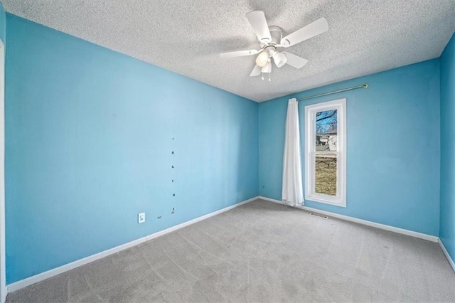 carpeted empty room with visible vents, a textured ceiling, a ceiling fan, and baseboards