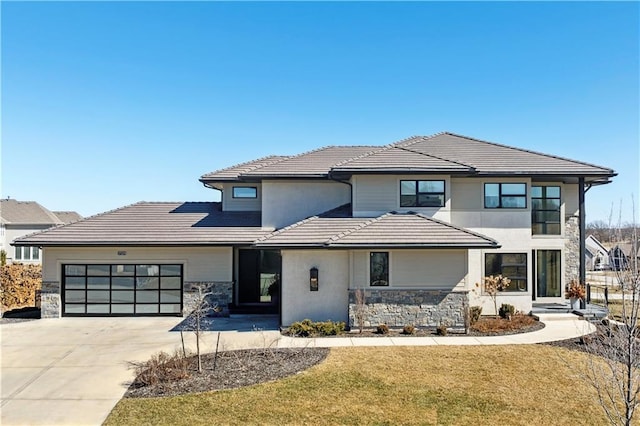 view of front of house featuring a garage, a tile roof, stone siding, concrete driveway, and a front yard