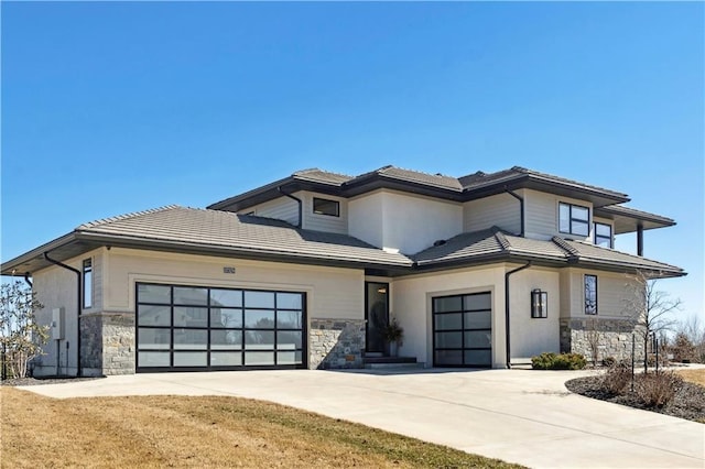 prairie-style house featuring stone siding, concrete driveway, and a tile roof