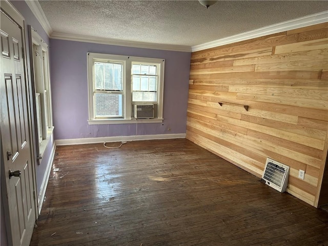 spare room with wooden walls, visible vents, dark wood-type flooring, a textured ceiling, and crown molding