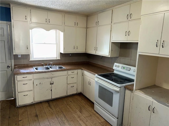 kitchen featuring dark countertops, electric range, a sink, a textured ceiling, and wood finished floors