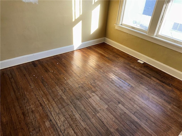 spare room with baseboards and wood finished floors