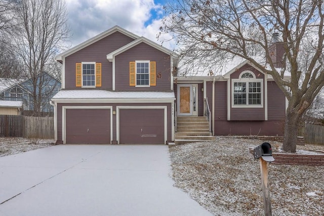 tri-level home with a garage, fence, and driveway