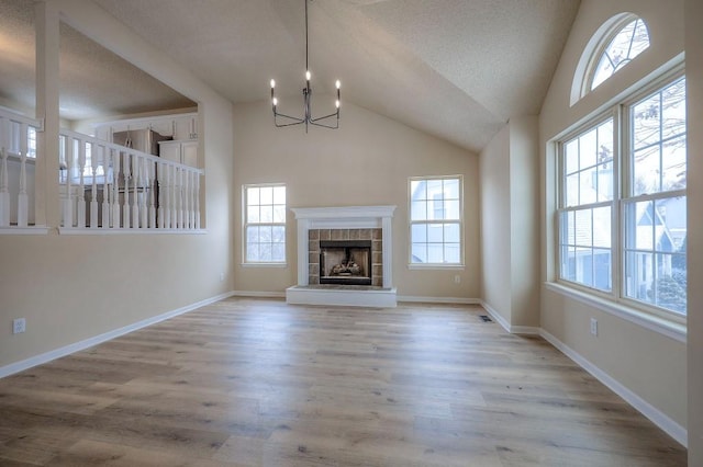 unfurnished living room featuring a wealth of natural light, light wood-type flooring, a fireplace, and baseboards